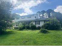Traditional two-story home with a lush green lawn and mature trees providing shade at 713 Pine Chase Ct, Lawrenceville, GA 30043