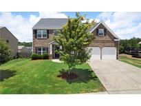 Charming two-story brick home featuring a well-manicured lawn and a two-car garage at 303 Horizon Trce, Loganville, GA 30052
