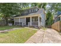 Charming two-story home featuring a screened-in front porch and mature trees at 1454 Beecher Sw St, Atlanta, GA 30310