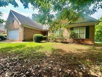 Charming brick home with a well-maintained lawn and mature trees providing shade at 1861 Crowell Sw Rd, Conyers, GA 30094