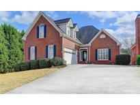 Charming red brick home featuring blue shutters, manicured landscaping, and a two-car garage at 2324 Blackberry Ct, Snellville, GA 30078