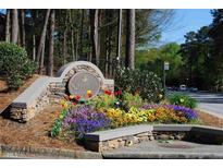 Community sign with landscaping featuring colorful flowers and stone construction at 3828 Woodridge Way, Tucker, GA 30084