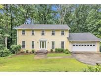 Charming two-story home with a lush lawn, attached garage, and mature trees providing ample shade at 3914 Granger Dr, Atlanta, GA 30341
