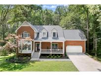 Traditional brick home with a manicured front yard, a covered porch, and an attached garage at 4392 Windsor Oaks Cir, Marietta, GA 30066