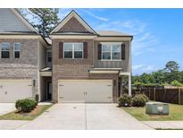 Charming two-story townhome with brick accents, attached garage, and well-manicured landscaping at 2700 Norwich Trce, Snellville, GA 30078