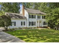Charming two-story home with a lush green lawn, black shutters, and mature trees at 1151 Roxboro Ne Cv, Atlanta, GA 30324