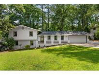 Charming two-story home with a well-manicured lawn, complemented by mature trees and a fresh, white facade at 4214 Williamsburg Dr, College Park, GA 30337