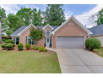 Charming brick home with a well-manicured lawn, a lovely entry door, and an attached two-car garage at 2420 Walnut Grove Way, Suwanee, GA 30024