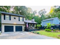 Charming split-level home featuring a two-car garage and inviting front porch nestled among lush trees at 3227 Due West Rd, Dallas, GA 30157