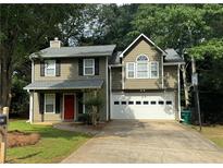 Charming two-story home featuring a two-car garage, red front door, and well-manicured lawn at 525 Cherokee Overlook Ct, Canton, GA 30115