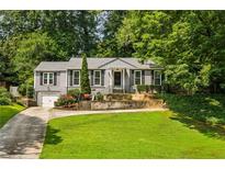 Charming home with a well-manicured front lawn, driveway, and lush landscaping with mature trees at 747 Channing Nw Dr, Atlanta, GA 30318