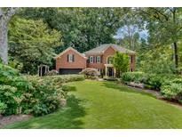Charming brick home with lush landscaping, a well-manicured lawn, and mature trees at 1676 Grove Park Way, Decatur, GA 30033
