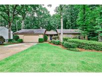 Charming single-story home with a lush green lawn, mature trees, and a two-car garage at 2528 Chimney Springs Dr, Marietta, GA 30062