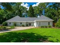 Charming one-story home with a well-manicured lawn, circular driveway, and lush landscaping at 4016 Dover Ave, Alpharetta, GA 30009