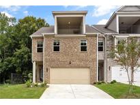 Charming brick townhome with a two-car garage and a balcony on the second floor at 5715 Rocky Falls Drive, Suwanee, GA 30024