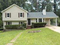 Charming two-story home features a well-maintained lawn, brick path, and a convenient carport for covered parking at 1380 Ashbrook Dr, Lawrenceville, GA 30043