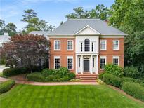 Charming brick home featuring manicured lawn and lush landscaping, offering timeless curb appeal at 2878 Wesley Heath Nw, Atlanta, GA 30327