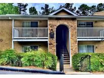 Inviting condo exterior with brick archway, white railings, and lush landscaping at 3120 Seven Pines Court # 203, Atlanta, GA 30339