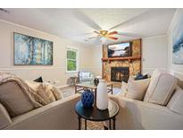 Inviting living room with stone fireplace, plush seating, ceiling fan, and stylish decor creating a cozy ambiance at 588 Benson Hurst Dr, Mableton, GA 30126