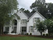 Charming two-story home with painted brick, arched entry, manicured lawn and mature trees at 7235 Compton Cir, Cumming, GA 30040