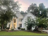 Charming, white two-story home with manicured lawn and mature trees at 7235 Compton Cir, Cumming, GA 30040
