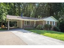 Charming brick home with a spacious carport and well-maintained front yard landscaping at 3390 Kenland Se Rd, Smyrna, GA 30082
