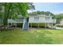 Charming home with a large front yard and a cozy porch, surrounded by mature trees and green grass at 6223 Emerald Springs Se Dr, Acworth, GA 30102