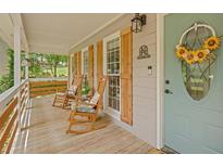 Charming front porch with rocking chairs, a wooden deck, and a decorative sunflower wreath on the front door at 425 Shelby Ln, Hiram, GA 30141