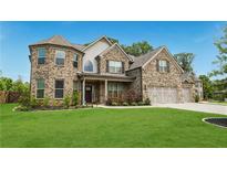 Beautiful two-story brick home with well-manicured lawn and attached two-car garage at 5381 Front Runner Ct, Sugar Hill, GA 30518
