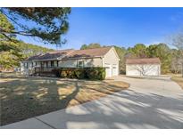 Charming ranch-style home with a well-manicured lawn, mature trees, and detached two-car garage at 140 Moseley Dr, Stockbridge, GA 30281