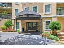Covered entrance of building featuring glass double doors, manicured shrubs and beautiful red flowers at 1 Biscayne Nw Dr # 112, Atlanta, GA 30309