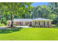 Charming brick ranch with beautiful landscaping and mature trees offers great curb appeal at 400 Little John Nw Dr, Lilburn, GA 30047