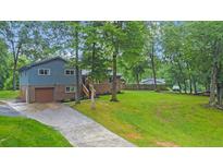 Two-story home with a gray exterior, brick accents, attached garage, a long driveway and a spacious front yard at 1031 Washington Ave, Woodstock, GA 30188
