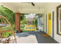 Inviting front porch with a hanging swing, ceiling fan, and charming yellow door at 307 S Mcdonough St, Decatur, GA 30030
