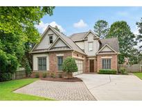 Charming two-story brick home with a well-manicured front yard and a spacious driveway on a sunny day at 1549 Lake Holcomb Ln, Marietta, GA 30062