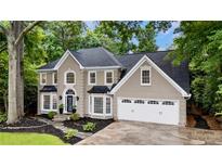 Elegant two-story home with a well-manicured lawn, a black roof and an attached garage at 910 Kings Arms Way, Johns Creek, GA 30022