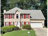 Charming two-story home with red shutters, a well-manicured lawn, and an attached two-car garage at 1019 Wolf Springs Ct, Lawrenceville, GA 30043