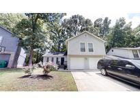 Charming two-story home featuring a two-car garage, complemented by lush landscaping and mature trees at 1169 Oaks Pl, Stone Mountain, GA 30083