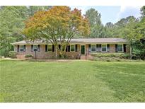 Charming brick home featuring a spacious lawn, mature trees and manicured shrubs at 501 Bridlepath Ln, Peachtree City, GA 30269