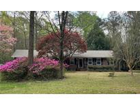 Charming single-story brick home featuring a lush front yard with colorful landscaping and mature trees at 501 Bridlepath Ln, Peachtree City, GA 30269