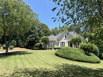 Charming home featuring manicured lawn and lush, mature landscaping, offering great curb appeal at 605 Meadows Creek Dr, Johns Creek, GA 30005