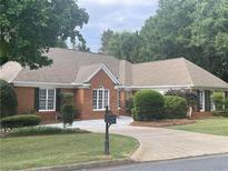 Charming one-story brick home with a well-maintained lawn, mature trees, and traditional architectural details at 5005 Johns Creek Ct, Alpharetta, GA 30022