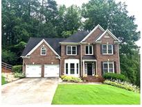 Charming brick two-story home featuring an attached two-car garage and a well-manicured lawn at 2045 Barrett Downs Dr, Cumming, GA 30040