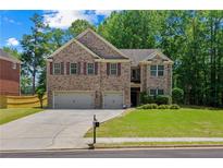 Charming brick two-story home featuring a manicured lawn and a two-car garage at 2015 Chapel Estates Lane Southeast Ln, Dacula, GA 30019