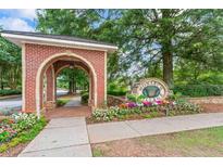 Charming brick entrance to the Monarch Village neighborhood with colorful flower beds and mature trees at 615 Brookwater Dr, Stockbridge, GA 30281