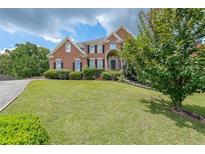 Charming brick home featuring a lush green lawn, manicured bushes and complemented by mature trees at 2684 Mountain Oaks Ct, Powder Springs, GA 30127