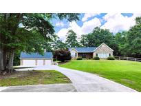 Charming stone home with a well-manicured lawn, long driveway, and detached garage at 5300 Haynes Creek Dr, Loganville, GA 30052
