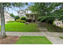 Charming two-story home with well-manicured lawn and lush landscaping, showcasing curb appeal and inviting entrance at 4944 Dovecote Trl, Suwanee, GA 30024