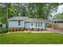 Charming blue home featuring a well-manicured lawn and a cozy covered parking area at 4981 Crowe Se Dr, Smyrna, GA 30082