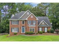 Charming brick two-story home with a blue front door, a manicured lawn, mature trees, and dark shutters at 992 Marbury Sw Ct, Marietta, GA 30064